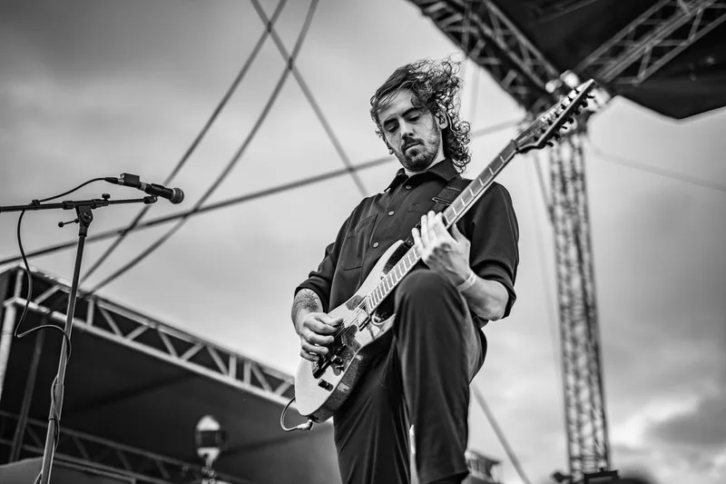 concert-Revnoir-Mozhell-guitariste-cheveux-ciel-nuages-noir-blanc