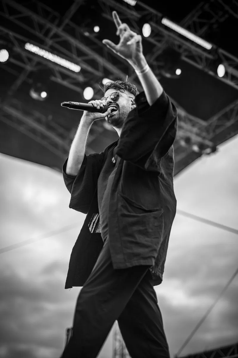 concert-Revnoir-Mozhell-chanteur-sourire-ciel-nuages-noir-blanc