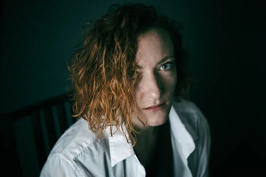 Portrait en studio d'une femme rousse au regard bleu intense, illustrant l'échange avec le modèle