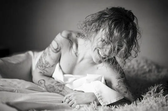 Portrait intimiste sur le vif d'une femme tatouée affichant un éclat de rire spontané