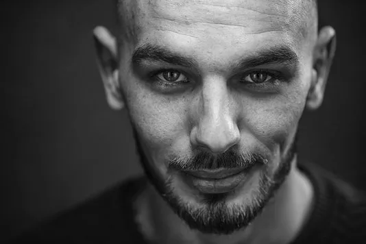 Cadrage serré de type headshot en studio mettant l'accent sur l'intensité du regard d'un homme
